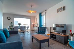 ein Wohnzimmer mit einem blauen Sofa und einem Fernseher in der Unterkunft Le Jardin du Golfe - En centre-ville avec parking in Sarzeau