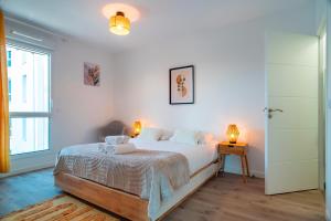 ein Schlafzimmer mit einem Bett mit weißer Bettwäsche und zwei Lampen in der Unterkunft Le Jardin du Golfe - En centre-ville avec parking in Sarzeau