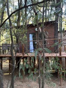 a log cabin with a wooden deck in the woods at Luxury Tranquil Treehouse & Hot Tub in Pretoria +27 photos