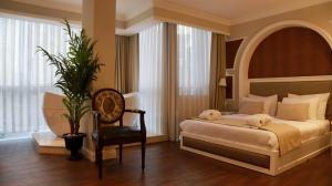 a bedroom with a bed and a chair and window at DBD Hotel Bayraklı in Bayrakli
