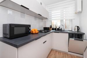 a kitchen with a counter top with a microwave at Warzywnicza Apartment Motława River by Noclegi Renters in Gdańsk