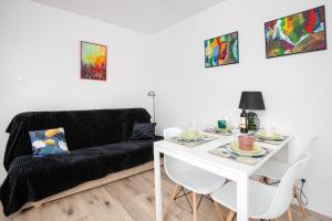 a living room with a black couch and a white table at Warzywnicza Apartment Motława River by Noclegi Renters in Gdańsk