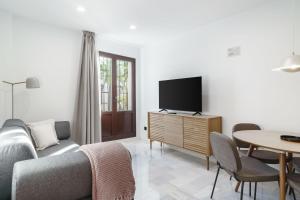 a living room with a couch and a tv and a table at Limehome Jerez de la Frontera Marqués de Casa-Domecq in Jerez de la Frontera