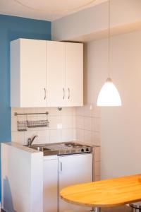 a kitchen with white cabinets and a wooden table at Pelagos Paradise Seafront Studio by Booking Kottas in Kalamitsi +17 photos