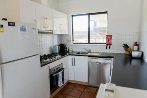 a small kitchen with a sink and a refrigerator at Apartment 231 in Gnarabup +2 photos