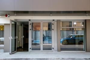 ein Gebäude mit Glastüren, in dessen Spiegelung sich ein Auto befindet in der Unterkunft BG Hotel in Sofia