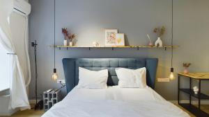 Un dormitorio con una cama azul con sábanas y almohadas blancas. en Piata Amzei 5, en Bucarest
