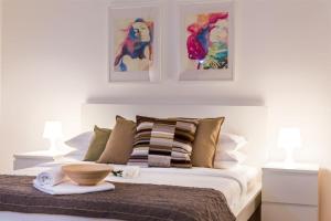 ein Schlafzimmer mit einem Bett mit drei Gemälden an der Wand in der Unterkunft Apartments Centro in Belgrad