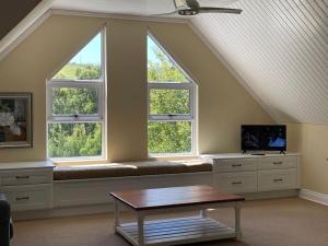 a room with three windows with a bench and a tv at Precious, Peaceful 3bedroom, 6 sleeper family home! in Balfour