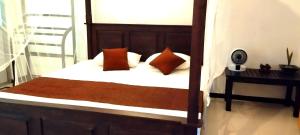 a bedroom with a bed with white sheets and orange pillows at Eco nest marakolliya in Tangalle