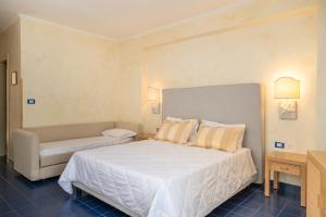 a bedroom with a large white bed and a couch at AH Premium Baia dei Faraglioni in Mattinata