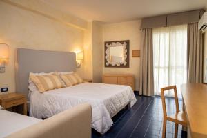 a hotel room with two beds and a window at AH Premium Baia dei Faraglioni in Mattinata