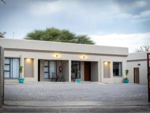 a white building with two chairs in front of it at Mango Self-catering Apartments in Ghanzi