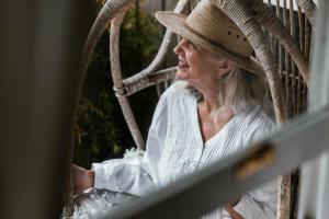 a woman wearing a hat sitting in a chair at Benambra Cottage c1860 in Queenscliff