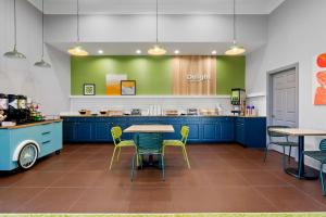 a kitchen with blue cabinets and chairs and a table at Spark by Hilton Daleville Roanoke North in Daleville