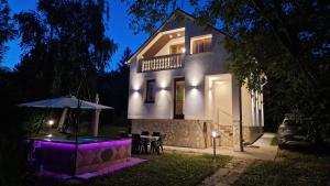 una casa con una mesa y una sombrilla por la noche en Pilis Hills View Deluxe House with Pool & AC near Bp, en Pilisszentiván