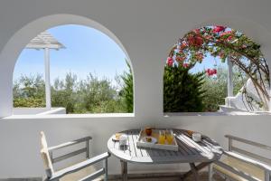 a table and chairs in a room with two windows at Anixis Studios Aliki Paros in Aliki