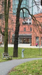 波兹南Le Cœur de la Ville的公园,公园有长凳和树,建筑