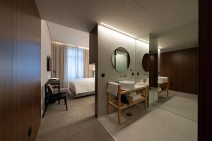 een badkamer met een wastafel, een bed en een spiegel bij Templo Hotel & SPA in Braga