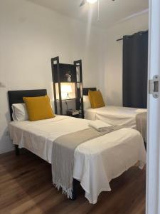 Habitación con 2 camas y almohadas blancas y amarillas. en Oporto 26, en Madrid
