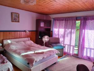 a bedroom with a bed and a chair and windows at Cheerful Bush House in Hepburn Springs