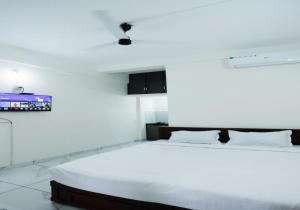 a white bedroom with a large bed and a tv at Hotel Diamond Castle in Manjeri