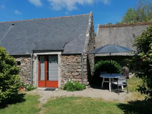 a stone house with a table and an umbrella at Gîtes à 30 min de la Pointe du Raz in Mahalon