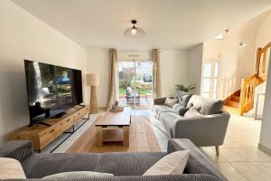 a living room with a couch and a flat screen tv at Maison de vacances tout confort - 300m des plages in Larmor-Plage