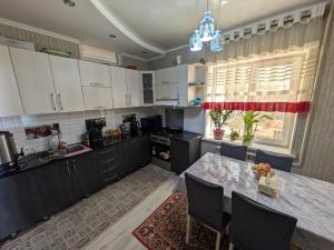 a kitchen with white cabinets and a table with chairs at Guest house Nuri in Karakol
