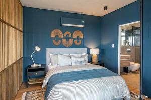 a blue bedroom with a bed and a blue wall at High Tide at Umdloti Resort in Umdloti +20 photos