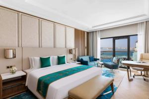 a bedroom with a large bed and a living room at Taj Exotica Resort & Spa, The Palm, Dubai in Dubai
