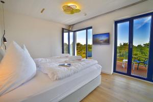 a white bedroom with a bed and large windows at Ferienwohnung Penthouse 17 im Haus Düne 7 Prora in Binz +55 photos