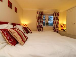 Un dormitorio con una gran cama blanca con almohadas rojas. en Woodside Cottage, en Skipton