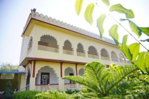 um edifício amarelo e branco com plantas verdes em frente em The Great Meva Palace Pushkar em Pushkar
