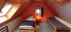 a attic room with two beds and two windows at Gîtes à 30 min de la Pointe du Raz in Mahalon