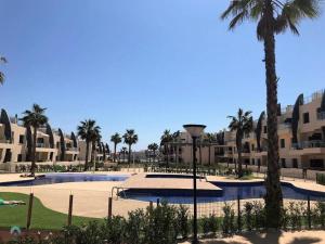 a resort with a swimming pool and palm trees at Ground floor apartment in Pilar de la Horadada - Mil Palmeras Beach in Pilar de la Horadada