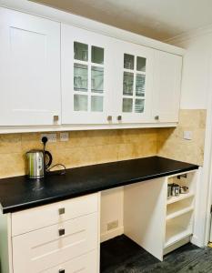 a kitchen with white cabinets and black counter top at Alcantara House in Southampton