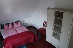 Un dormitorio con una cama con almohadas rosas y un armario. en Ostsee, en Diedrichshagen