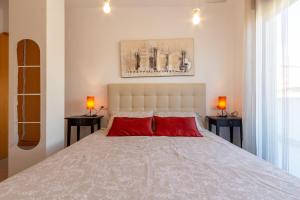 Un dormitorio con una gran cama blanca con almohadas rojas. en Apartamento en El Campello, España, en El Campello 32 fotos más