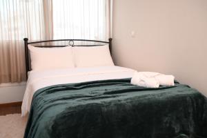 a bed with a green blanket and white pillows at Dione Central Loft in Heraklio Town