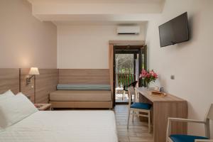 a hotel room with a bed and a desk with a television at Hotel Portoconte in Porto Conte