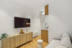 a living room with a couch and a flat screen tv at Lavie Maison Hot Tub and AC Near Arc de Triomphe in Paris