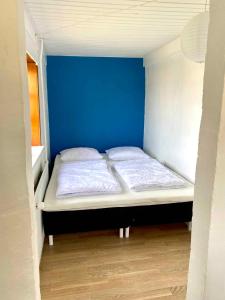 un petit lit dans une chambre avec un mur bleu dans l'établissement Charming Cottage In The Best Hc Andersen Style, à Frørup 8 autres photos