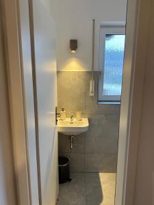 a small bathroom with a sink and a window at Deluxe-Family Apartment mit Terrasse, Küche & Parkplatz in Offenburg