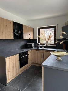 a kitchen with wooden cabinets and a black counter top at Deluxe-Family Apartment mit Terrasse, Küche & Parkplatz in Offenburg +8 photos