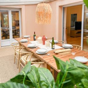 einen Holztisch mit weißen Tellern und Weinflaschen in der Unterkunft Grande maison chaleureuse à Bouliac in Bouliac