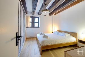 Schlafzimmer mit einem Bett mit weißer Bettwäsche und Holzböden in der Unterkunft Appartement avec 2 chambres, bureau et wifi fibre in Tours
