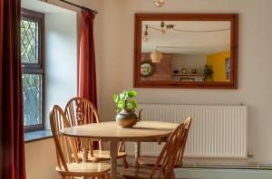einen Esstisch mit einer Topfpflanze darauf in der Unterkunft Cosy Cottage nr The Cotswolds Private Parking in Charfield