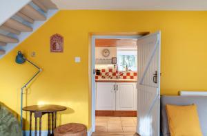 eine Küche mit gelben Wänden und einem Tisch in einem Zimmer in der Unterkunft Cosy Cottage nr The Cotswolds Private Parking in Charfield