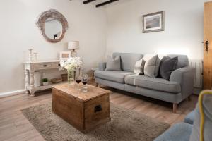 een woonkamer met een bank en een tafel met wijnglazen bij Hexham Cottage by Coast & Country Stays in Seahouses